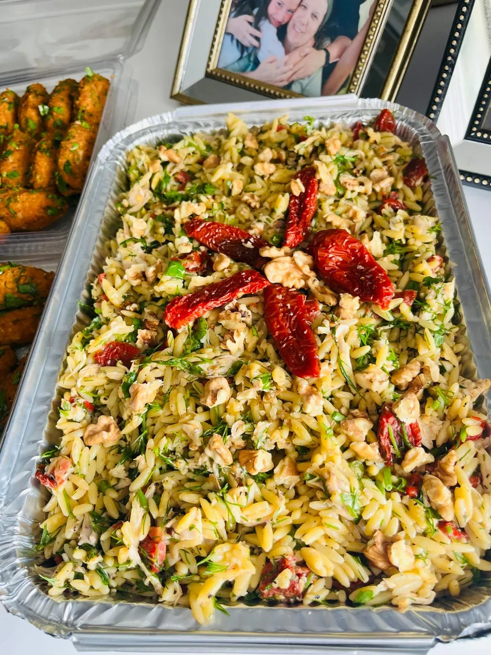 Alüminyum kapta, üzerinde kuru domates ve ceviz bulunan dereotlu arpa şehriye salatası